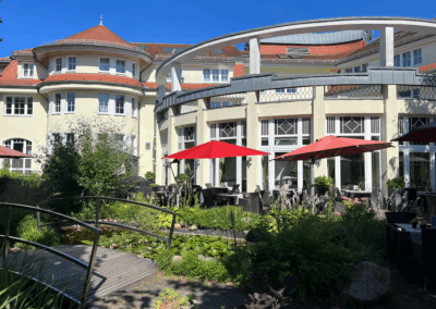 Terrasse mit Sonnenschirmen vor dem Gebäude des Wirtshaus Alpinia