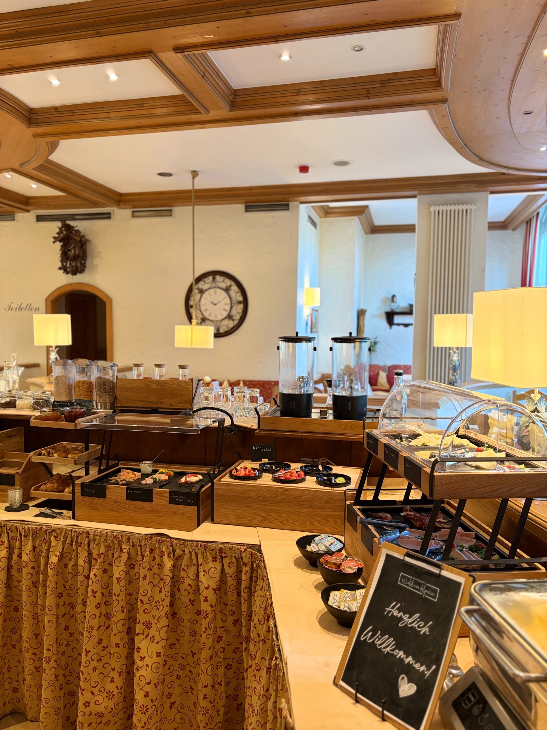 Reichhaltiges Frühstücksbuffet mit Lachs, Aufschnitt, Gebäck und Getränken im Landhaus Alpinia