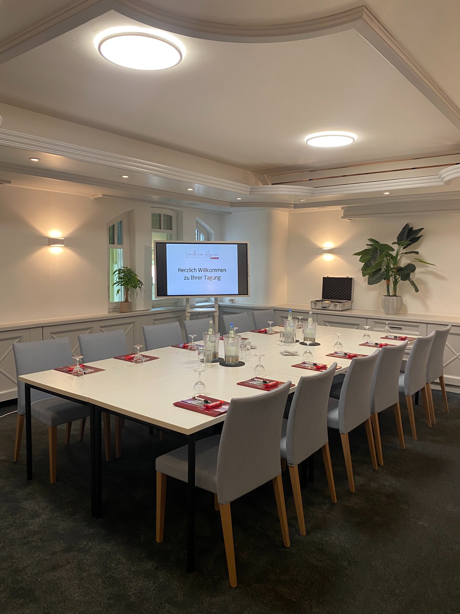 Moderner Tagungsraum im Landhaus Alpinia mit eingedecktem Konferenztisch und Praesentationsbildschirm